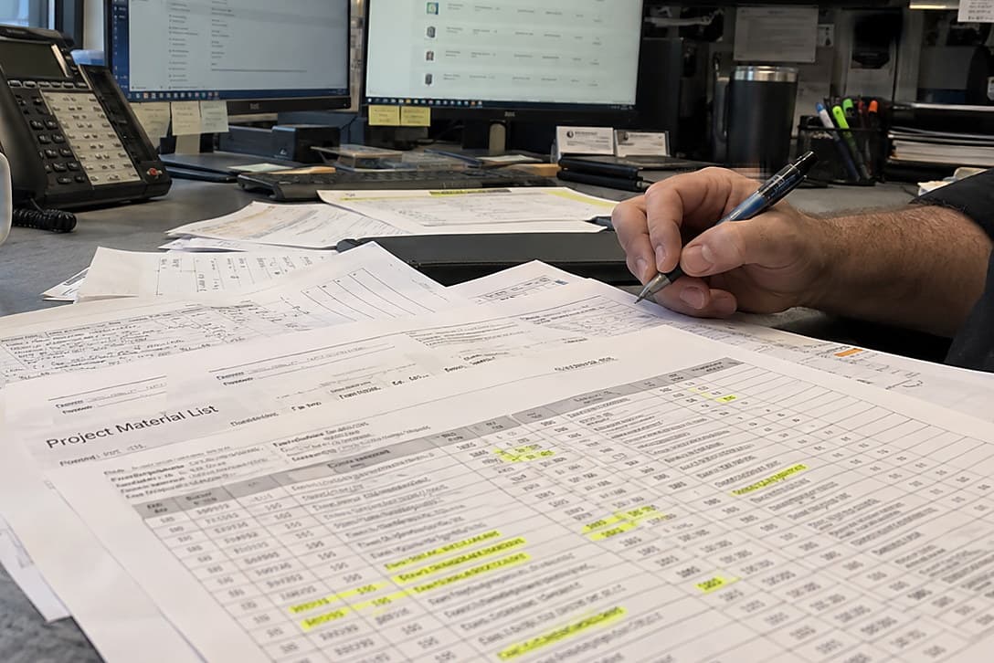 A rep’s hand holding a pen over a printed material list with highlighted lines.